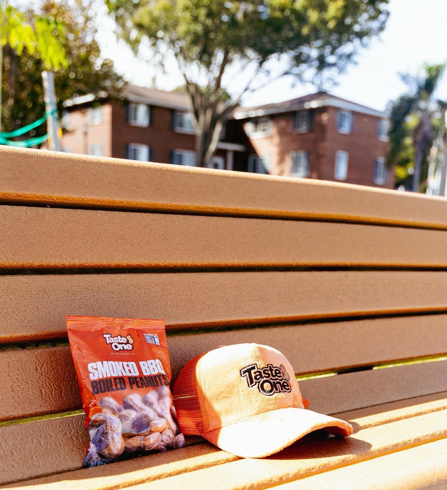 A bag and cap resting on a bench with an apartment building in the background